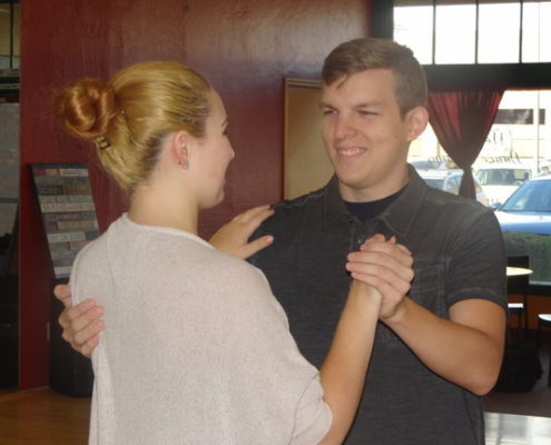 A blonde woman dancing with a man in black