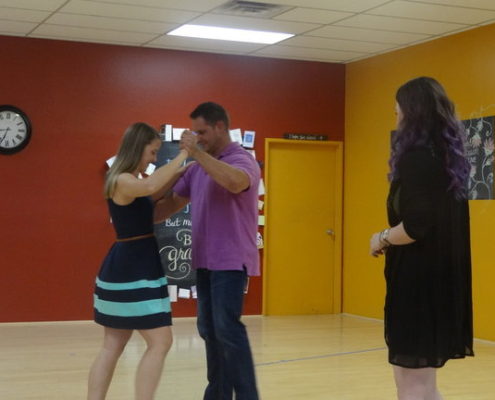 A woman in a blue dress dancing with a man in a purple shirt